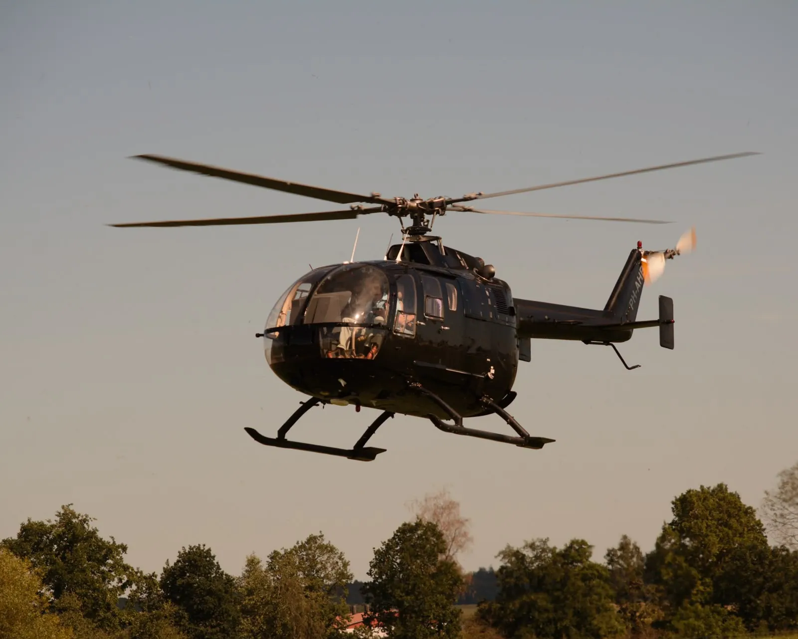 MBB BO105 PH-AHB im Anflug über einer Baumreihe
