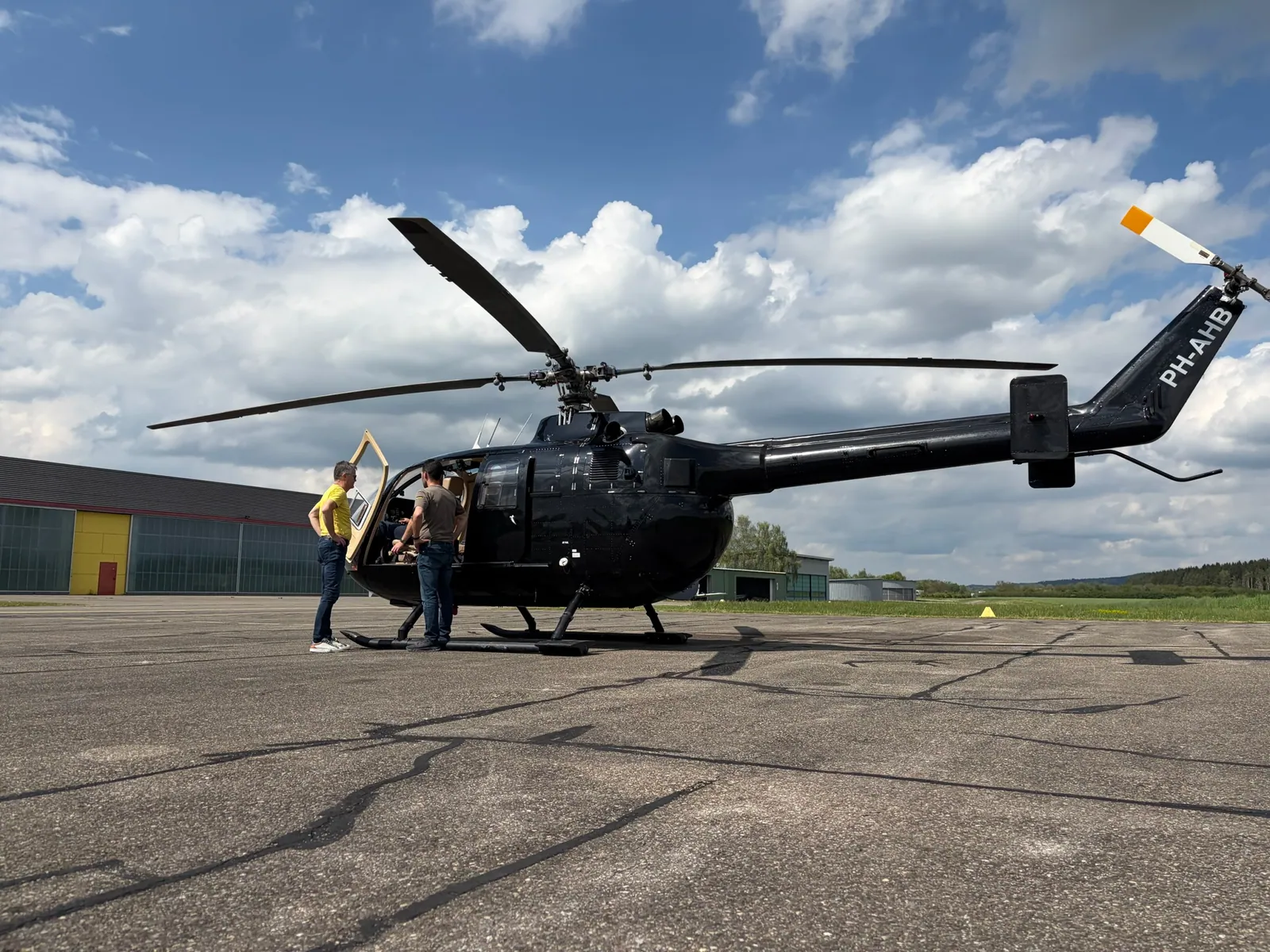 Zwei Personen an der geöffneten BO105 PH-AHB auf dem Vorfeld