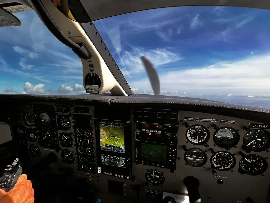 Blick aus einem Cockpit auf Instrumente und den Himmel im Flug