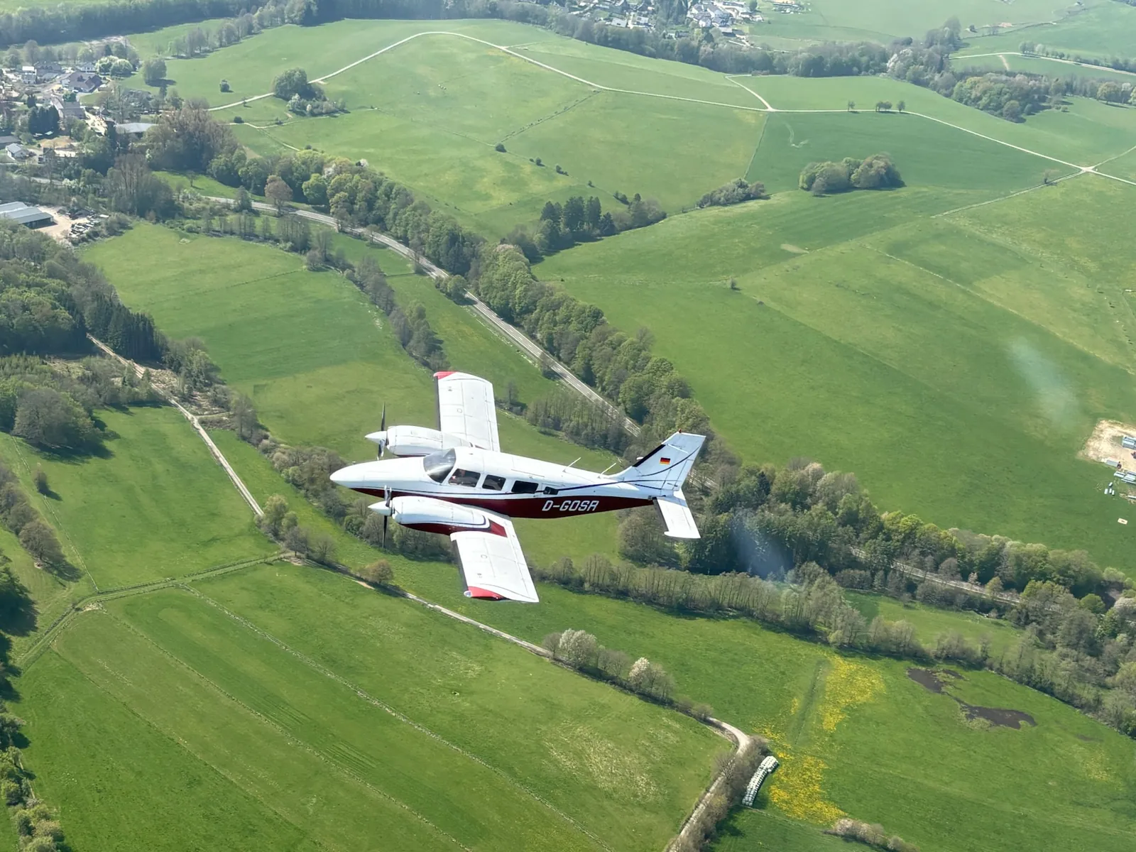 Piper Seneca D-GOSR im Flug über grüner Landschaft
