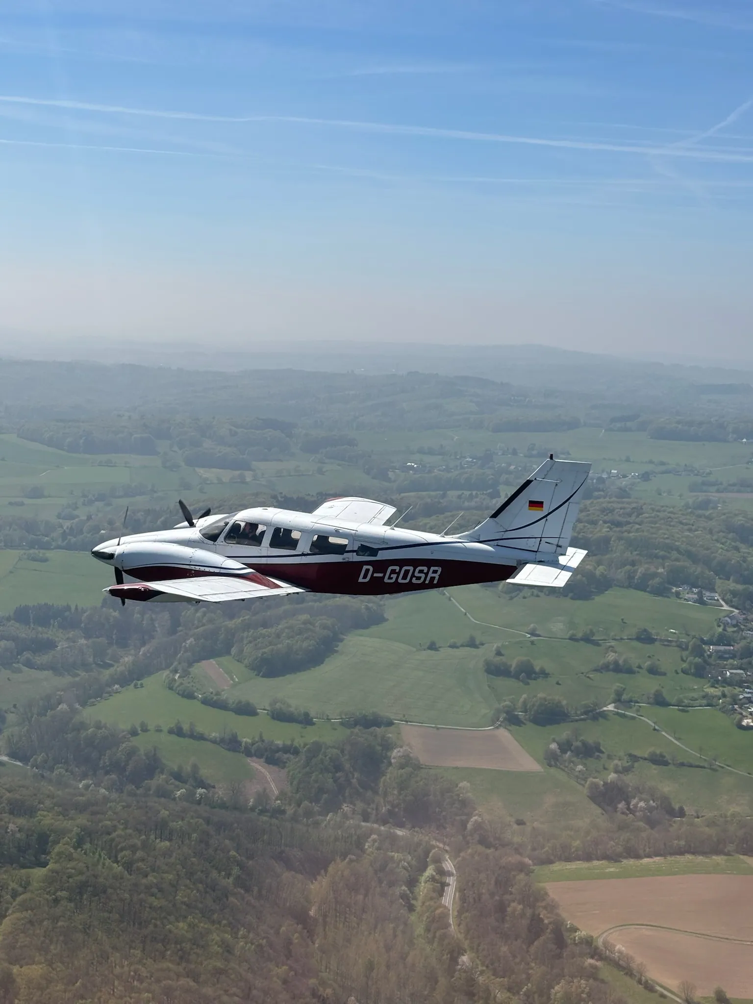 Piper Seneca D-GOSR im Flug über grüner Landschaft